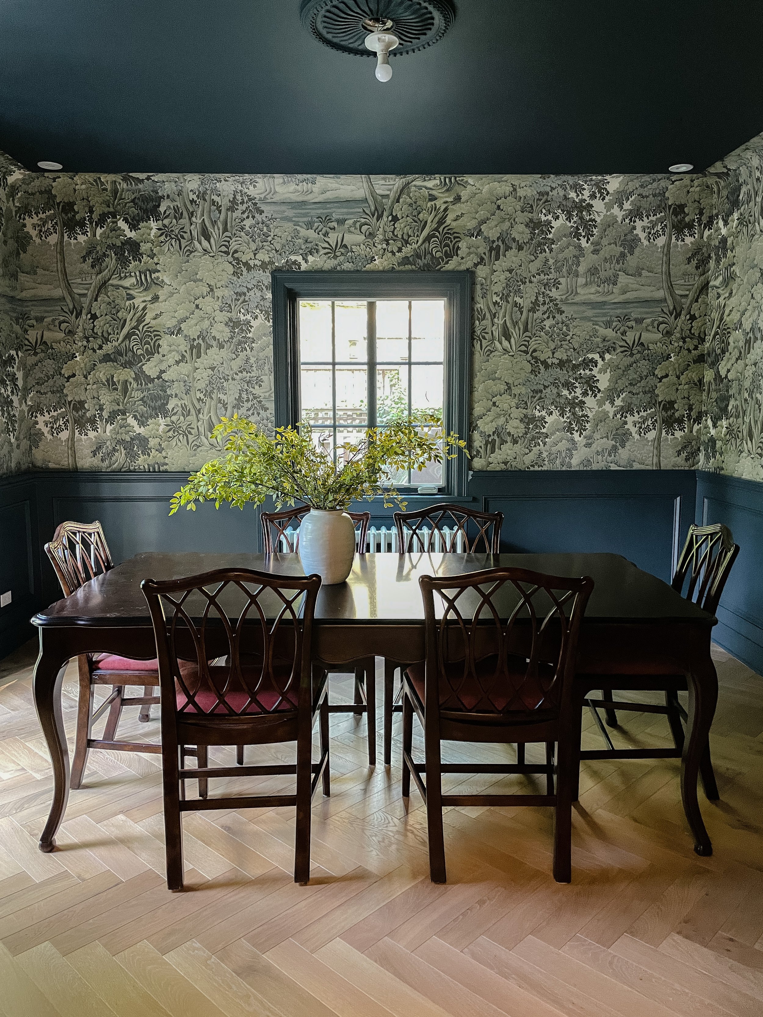 Moody dining room featuring botanical wallpaper